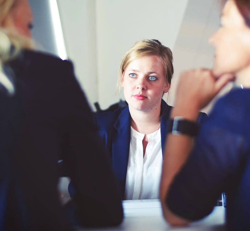 A woman dressed in suit sitting in a meeting 